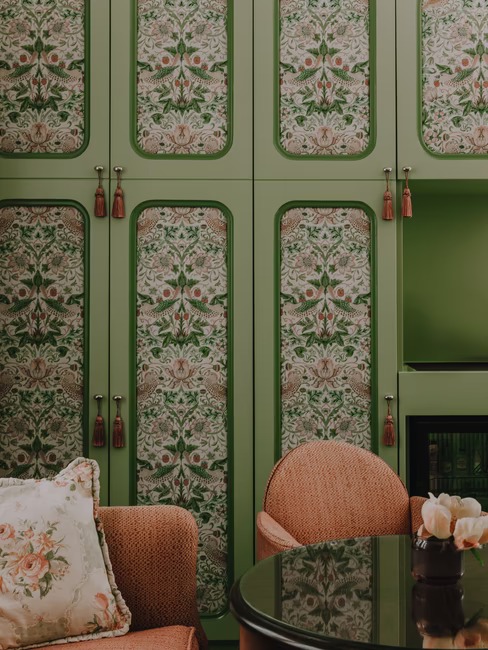 Der große grüne Schrank mit einem davorstehenden Sofa.
