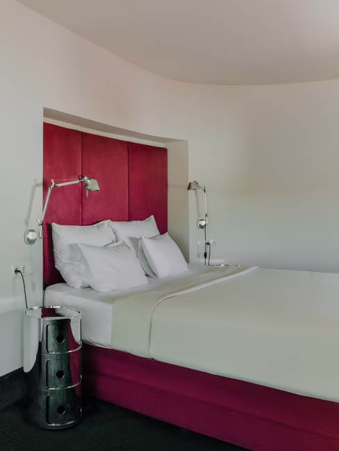 Das Doppelbett mit den Nachttischlampen auf beiden Seiten und einem grünen Bild, das neben dem Bett aufgehängt wurde.
