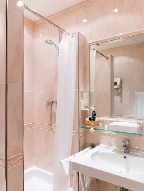 Badezimmer mit Dusche, großem Spiegel und Waschbecken