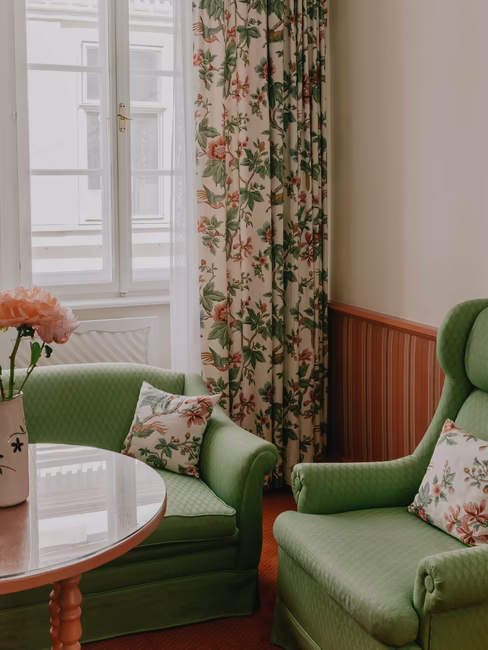 Sitzecke mit zwei großen grünen Stühlen mit Polstern und großem Fenster inkl. Gardinen mit Blumen
