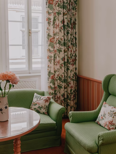 Sitzecke mit zwei großen grünen Stühlen mit Polstern und großem Fenster inkl. Gardinen mit Blumen