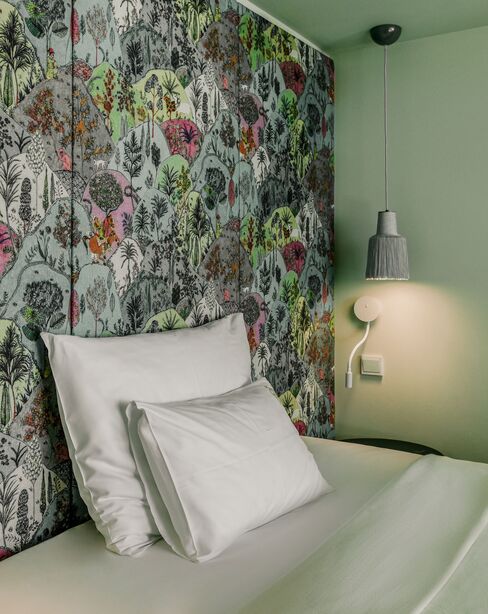 Das Einzelbett mit zwei von der Decke herabhängenden Lampen und einem farbenfrohen Hintergrund hinter dem Bett.
