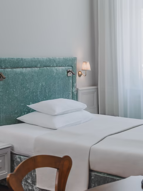 Einzelzimmer in Himmelblau / grau Design mit großem EZ Bett, Nachttisch und Schreibtisch