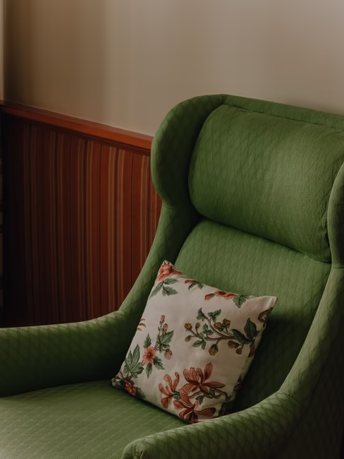 Der Sessel im Zimmer mit einem dekorativen Kissen.
